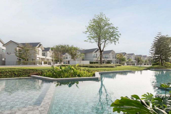 The communal pool along the lawn: the water runs to the far edge, with a row of two-storey houses and a single tree behind it