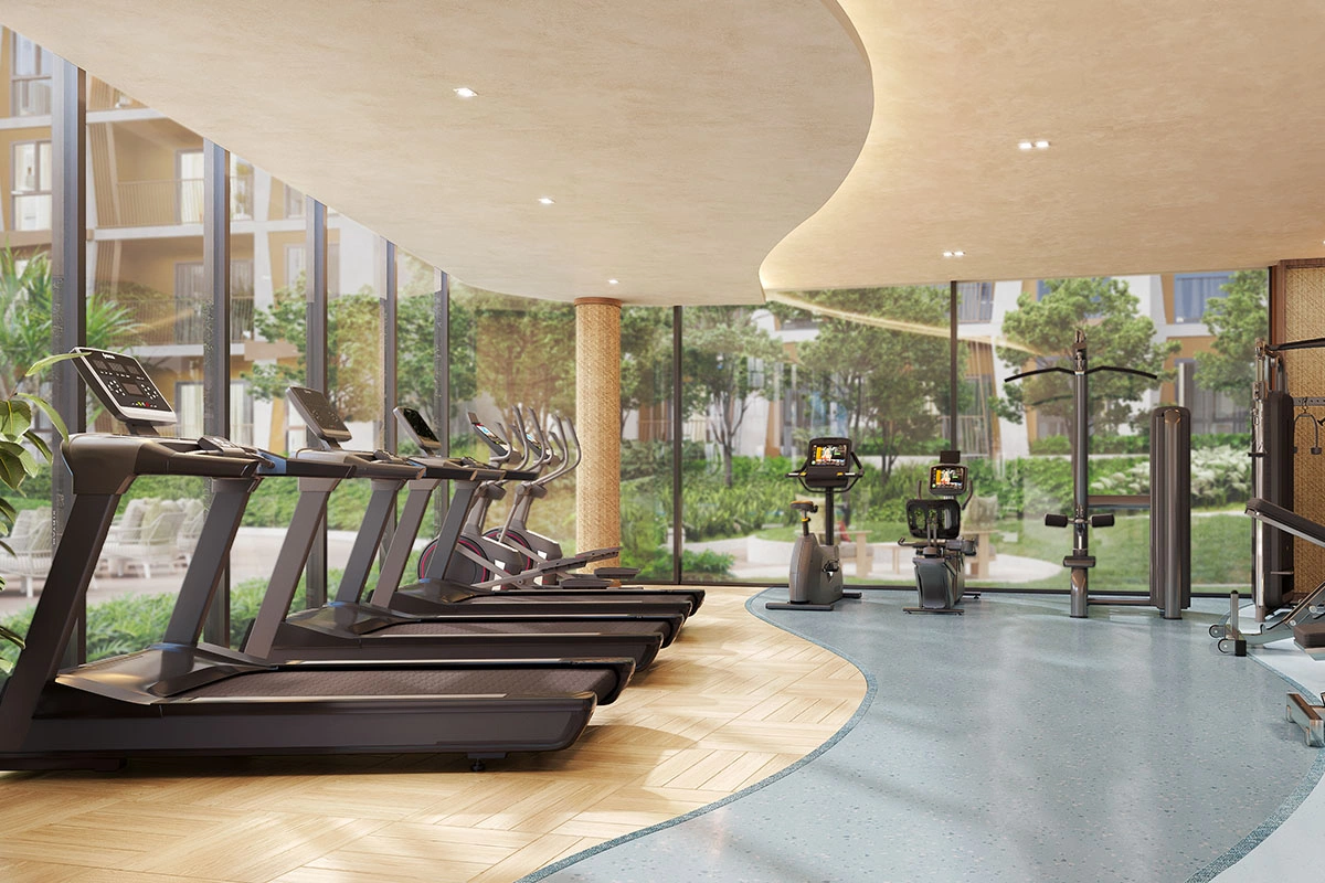 The fitness room: treadmills and exercise bikes along a glass wall, with the garden and buildings beyond