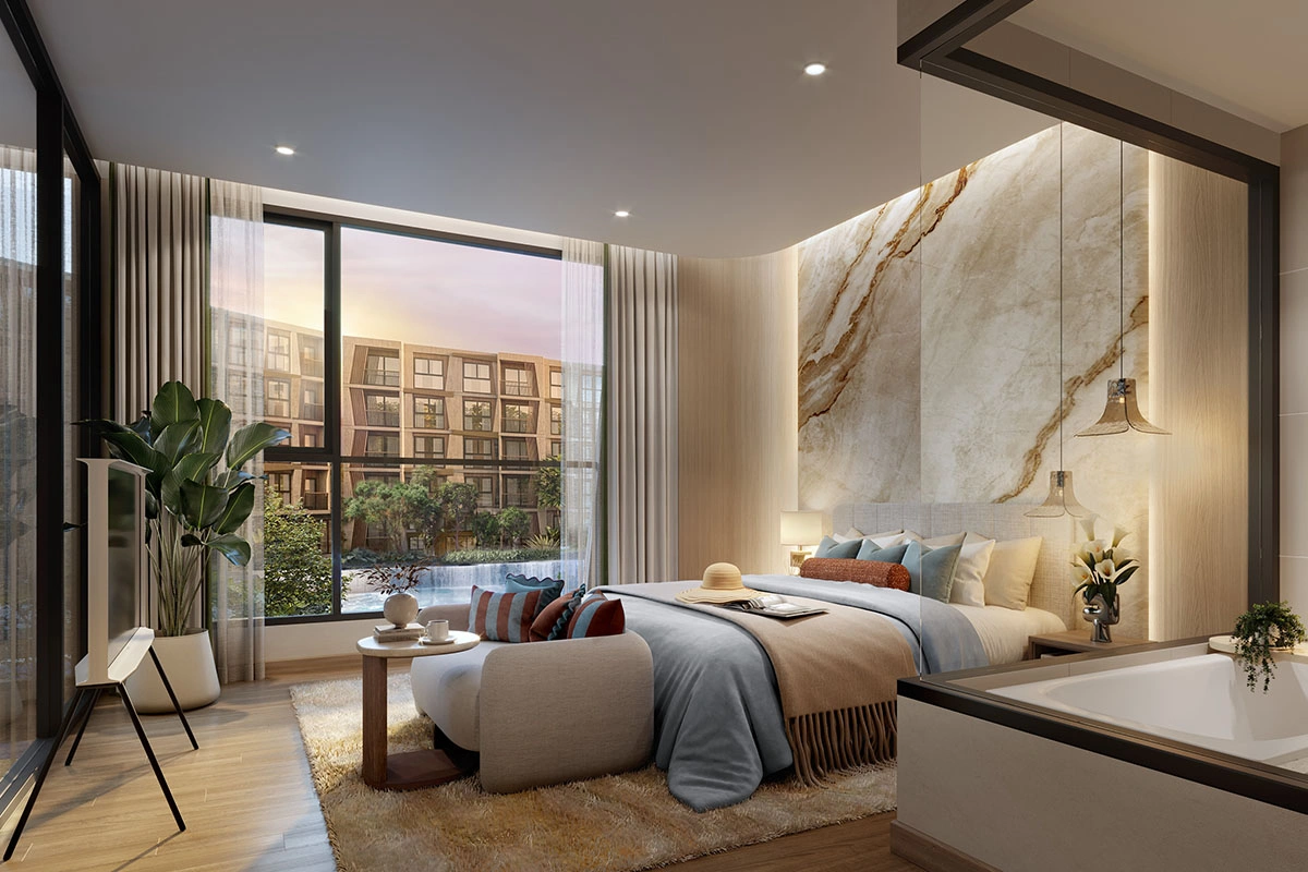 A villa's master bedroom: a bathtub by the glass wall, the bed against a stone-look panel and a view of the pool and buildings