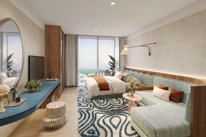 Шоу-рум планировки, где комната подписана BEDROOM & LIVING AREA: кровать и диван в одном объёме, длинная синяя консоль с зеркалом, дверь на балкон с видом на море