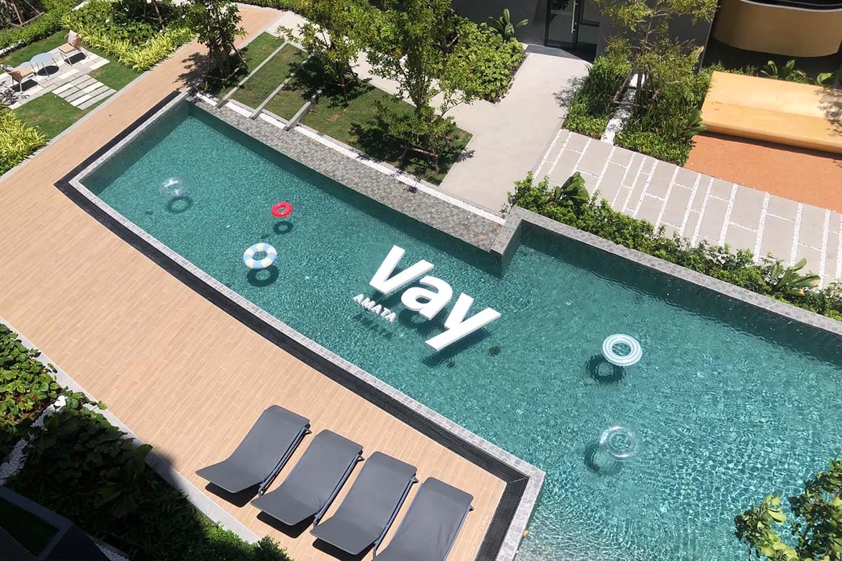 The pool from above: the letters Vay AMATA laid into its floor, four dark loungers along the timber deck and inflatable rings in the water