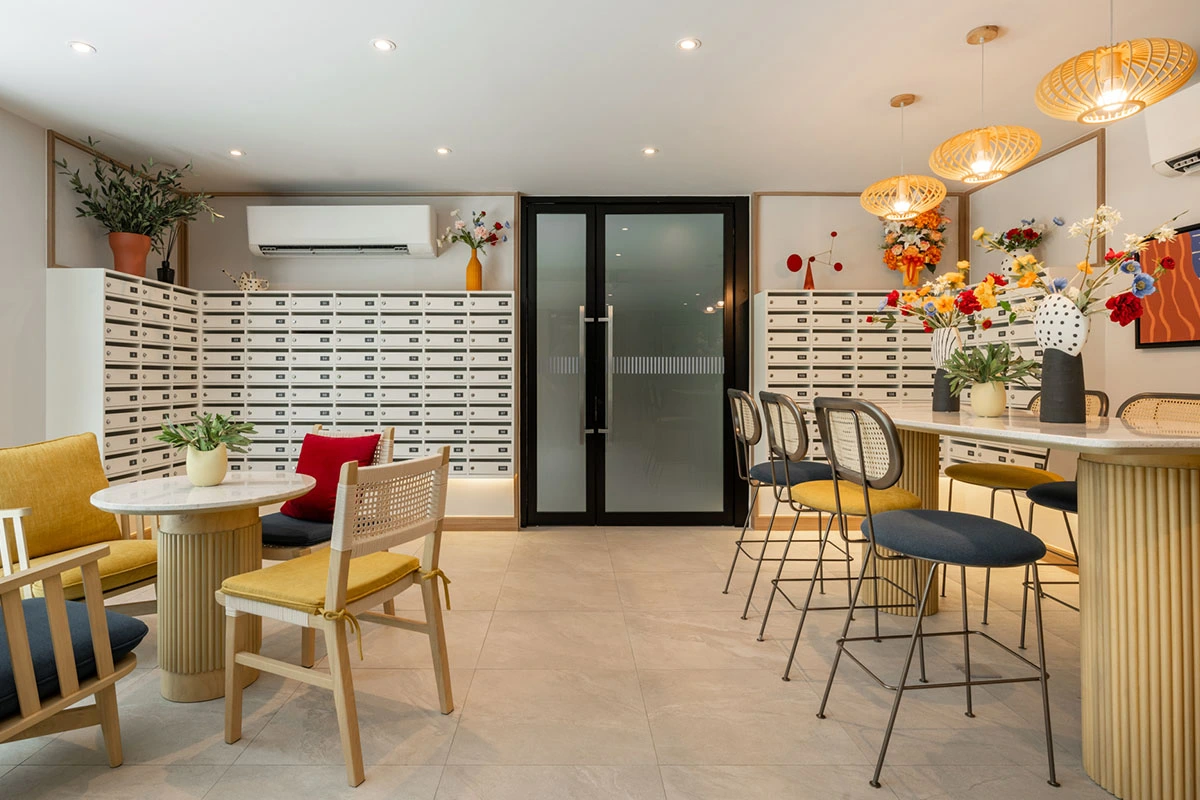 The mail area of the lobby: walls of letterbox cells, frosted glass doors in the middle, a bar counter with high stools and woven pendant lamps