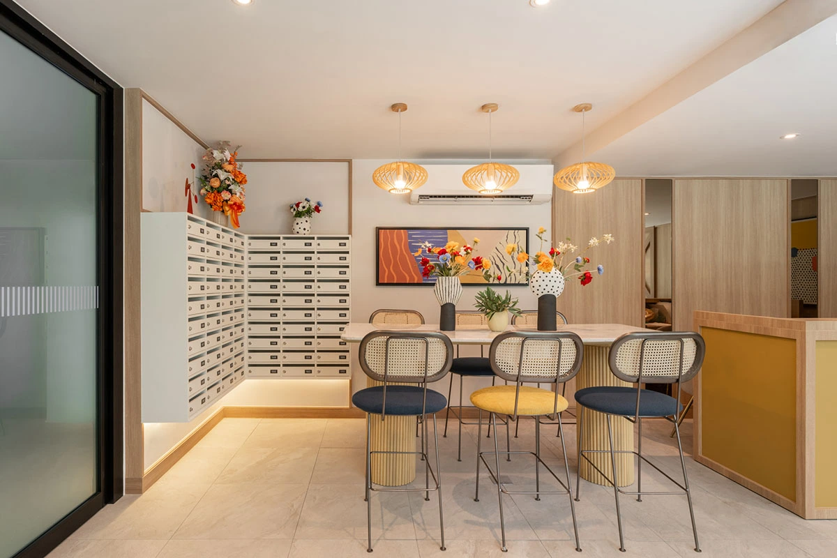 The same area from the other side: a high communal table for six, a painting above it, vases of flowers and letterbox cells along the wall