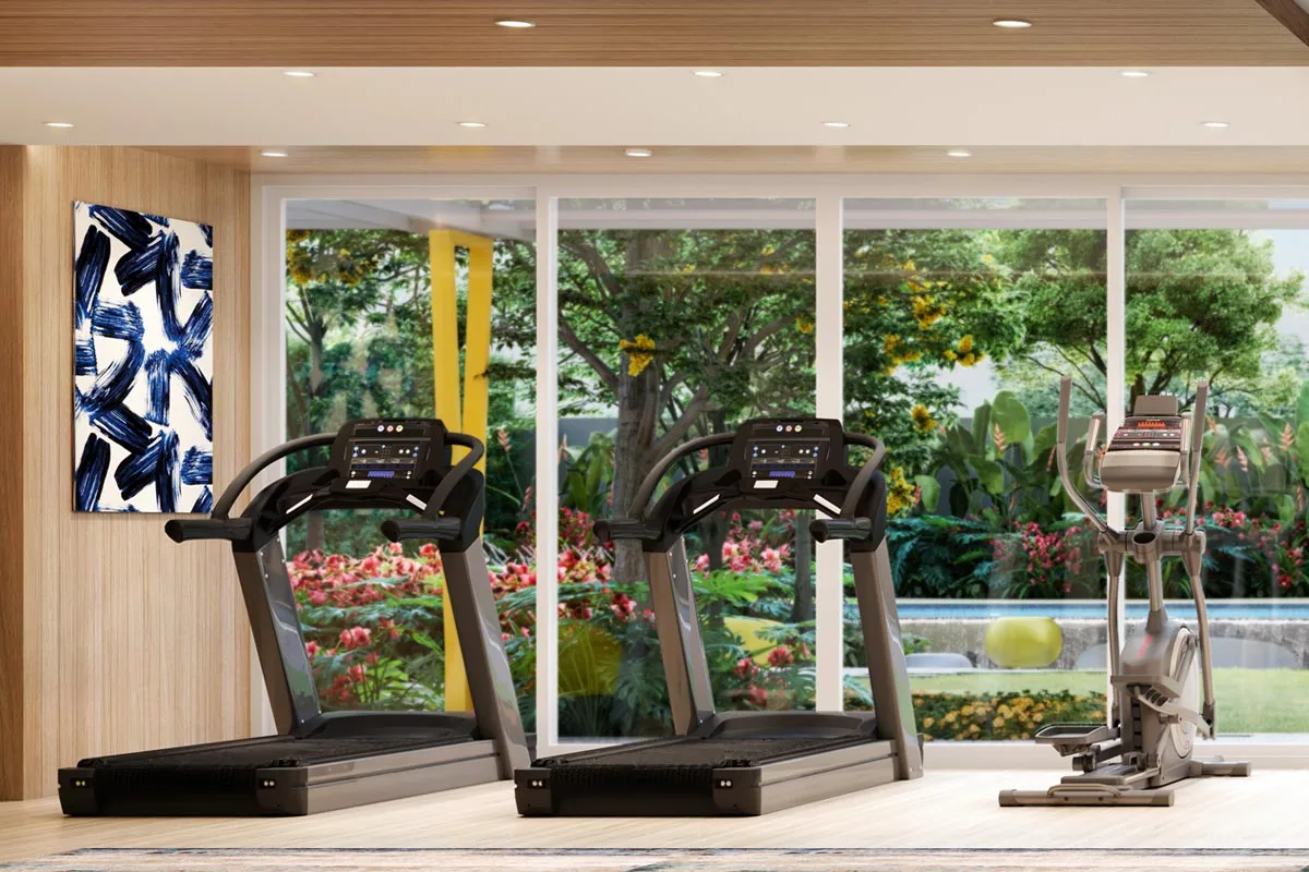 The gym: two treadmills and a cross-trainer at full-height glass, with the garden and the edge of the pool beyond