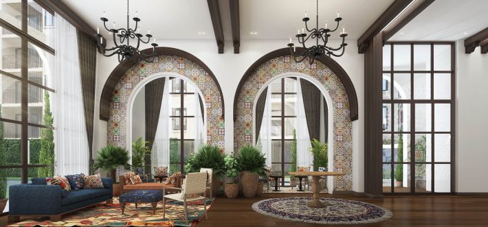 The lobby: two tall arches framed in patterned ceramic tile, wrought-iron chandeliers on timber beams, a blue sofa and patterned rugs