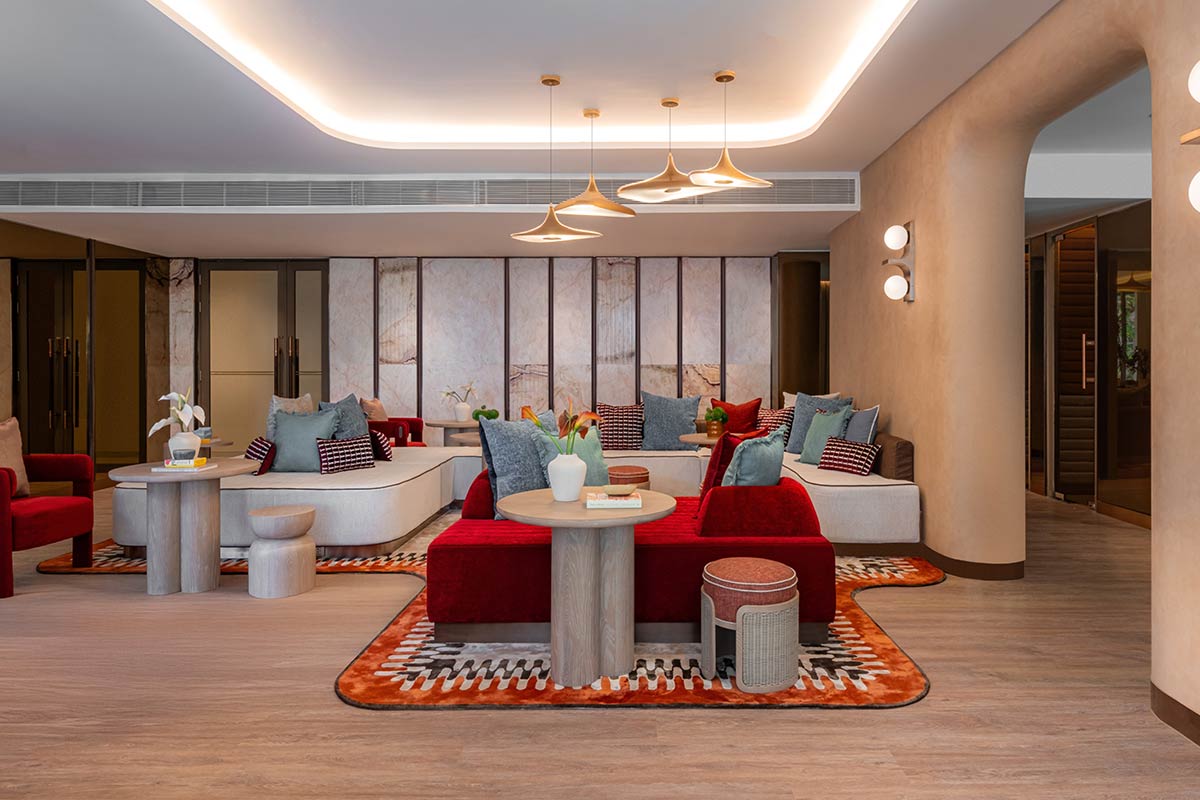 The retreat area of the co-working space: pale marble panels, red and cream sofas, an orange rug with a geometric pattern and rounded walls