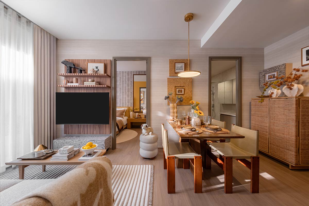 A show unit: the living room with a television on a timber panel, a dining table with benches, and a bedroom and a shower room through two openings