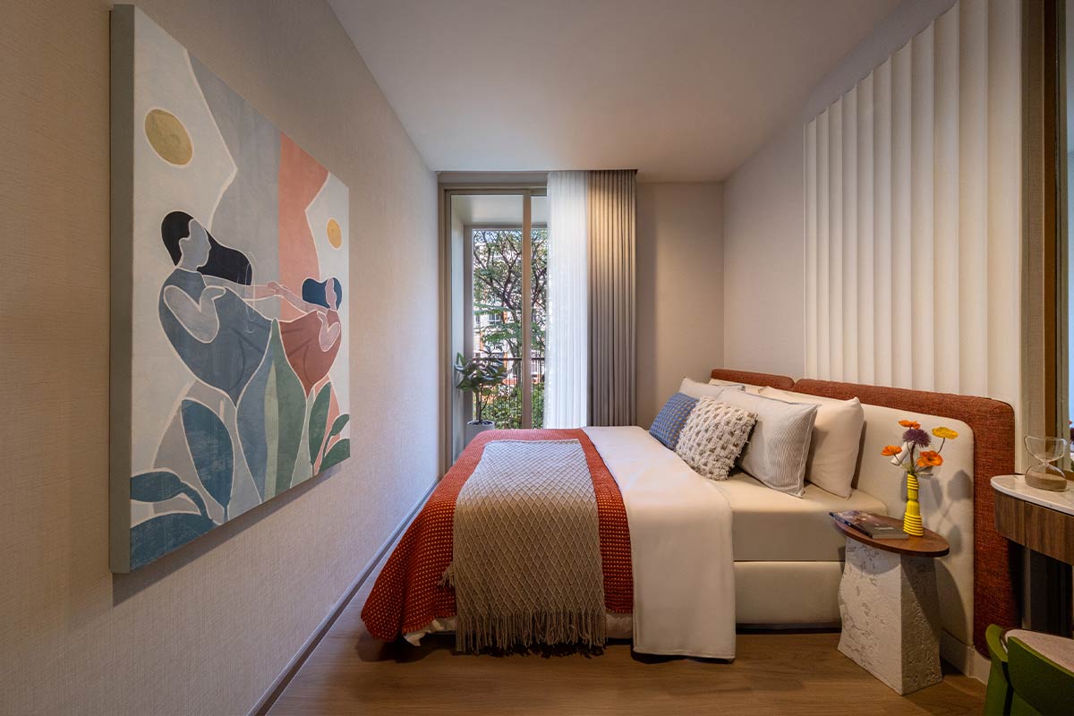 A show-unit bedroom: a bed with an upholstered headboard against a ribbed wall, a floor-to-ceiling window with a railing and a large painting opposite