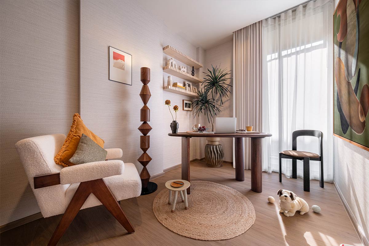 A show-unit room furnished as a study: a round table with a laptop at the floor-to-ceiling window, an armchair, shelves in a niche and a toy bulldog on the floor