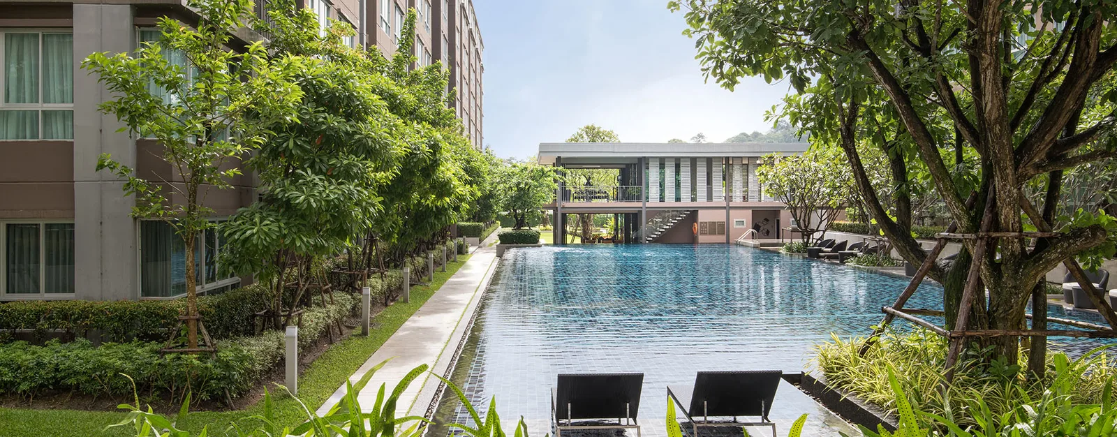 The courtyard between the buildings: a pool along the walkway, greenery on both sides and a linking gallery at the far end