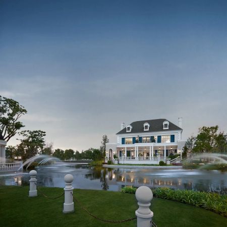 The clubhouse on the far bank of the pond, fountains and a balustrade along the water