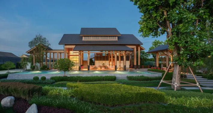 The clubhouse: an open veranda under a pitched roof, an old tree and grasses in front of the entrance