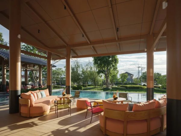 The sheltered lounge: round sofas, timber columns and the pool beyond