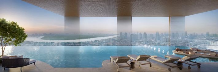 The upper-level pool: water to the edge, loungers in the shade and the city beyond