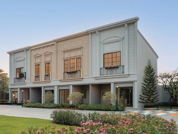 Units with arched windows and a mansard roof, a flower bed along the drive