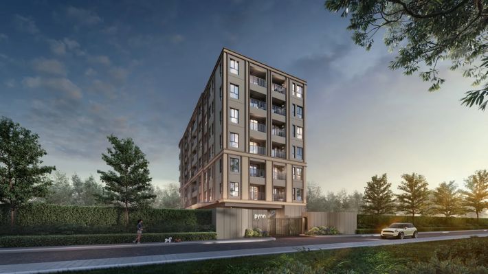 The building from the lane: seven storeys, brick cladding, trees along the drive