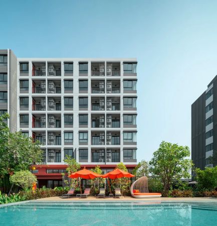 The building above the pool: red parasols and loungers at the water's edge