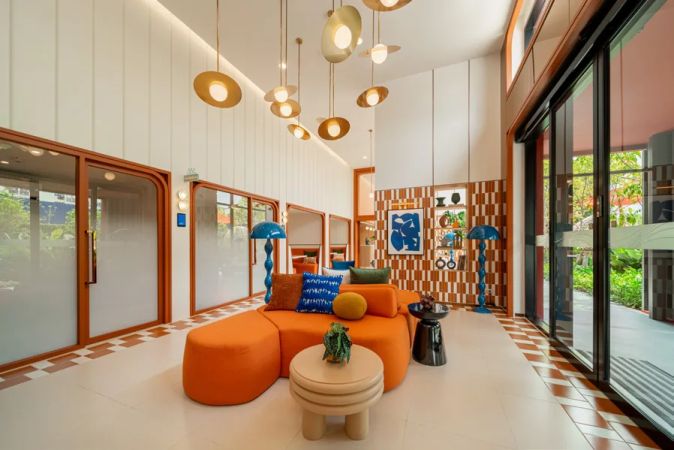 The double-height lobby: an orange sofa, brass pendants and a way out to the garden