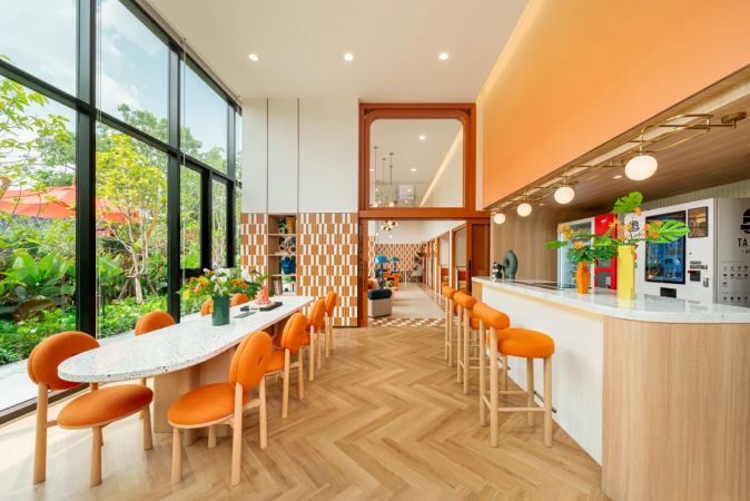 The communal kitchen and long table by the full-height window, the bar counter to the right
