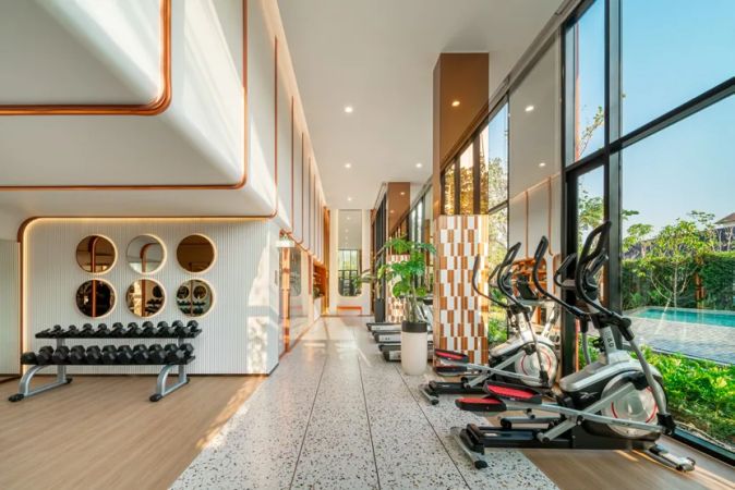 The gym along the glazed gallery: dumbbells, cross-trainers and a view of the pool