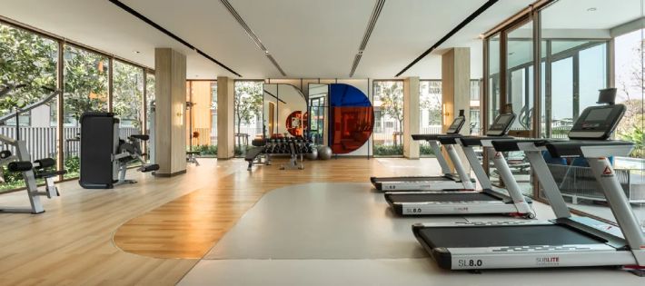 The gym with treadmills along the glazing, greenery outside