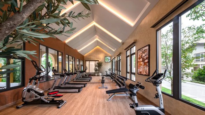 The gym with machines under a pitched roof and full-height glazing