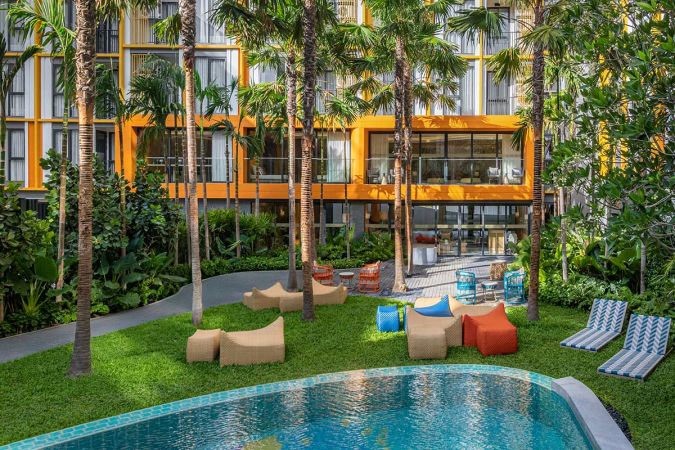Lawn with bean bags and sun loungers between the pool and the co-working pavilion
