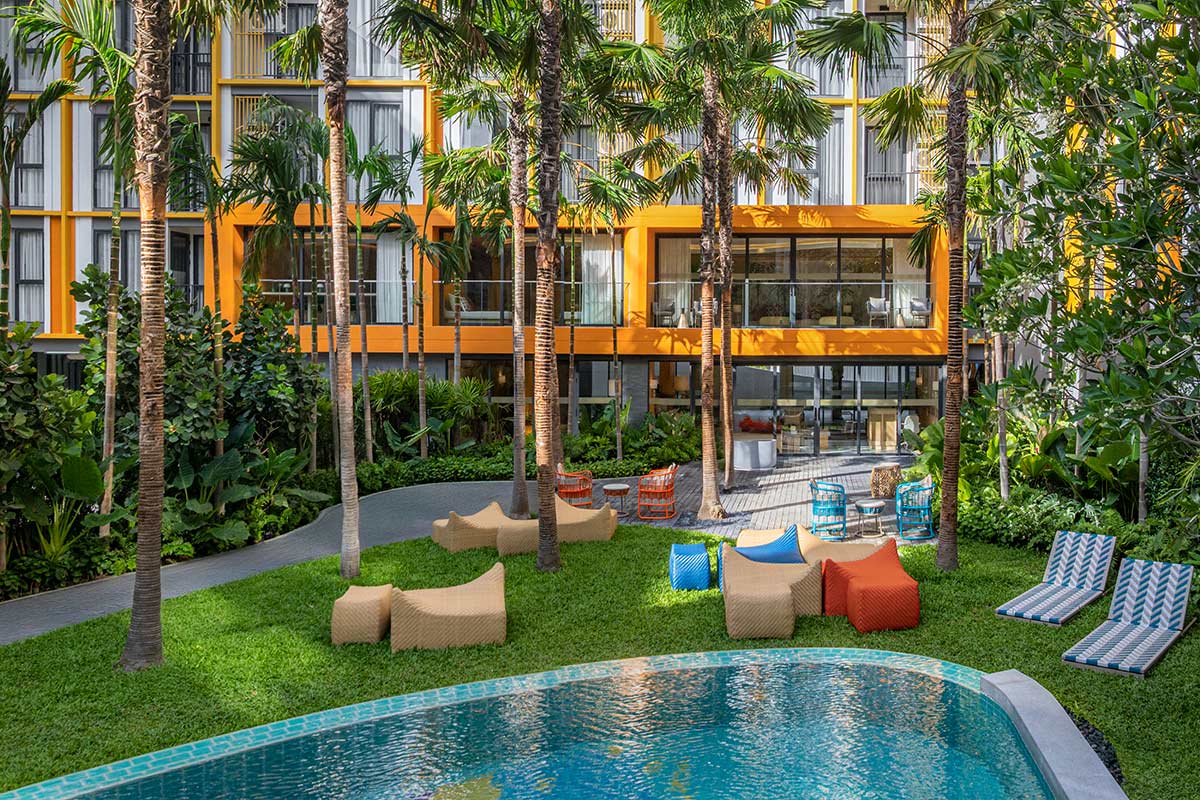 Lawn with bean bags and sun loungers between the pool and the co-working pavilion