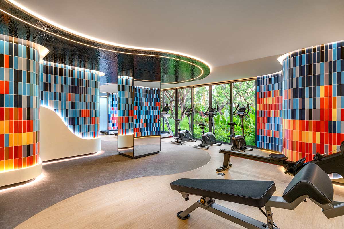 Fitness room: treadmills and weight benches, walls clad in coloured tiles