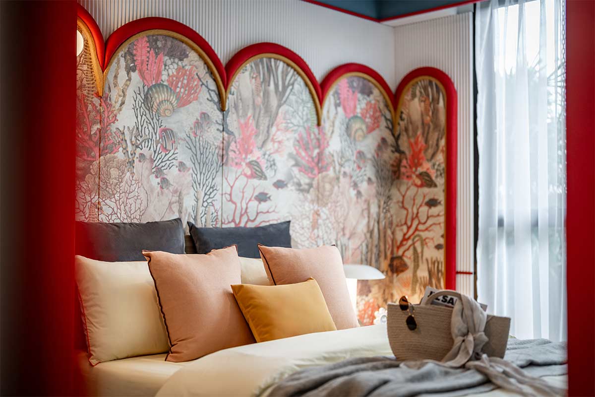 Show unit bedroom: the bed against a wall with a coral mural