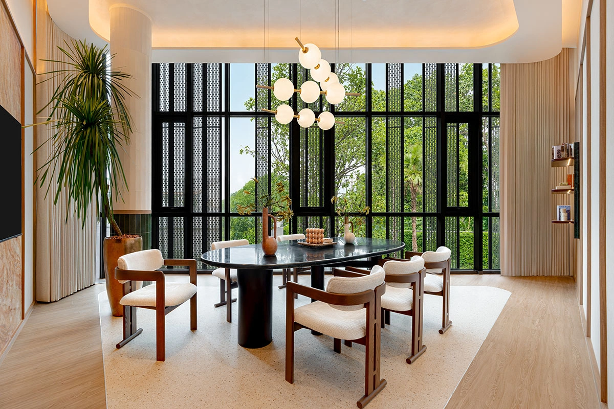 The meeting area of the co-working space: a black oval table with wooden chairs, patterned black screens over full-height windows and greenery outside