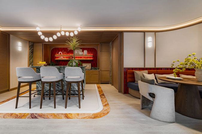 The co-kitchen: a bar counter with three stools, a niche lit in red and, further on, a red banquette with a dining table