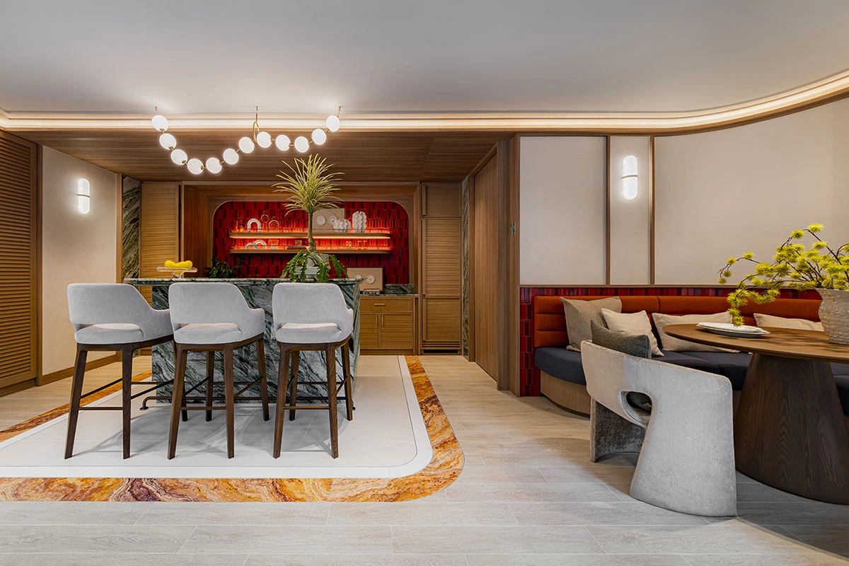 The co-kitchen: a bar counter with three stools, a niche lit in red and, further on, a red banquette with a dining table