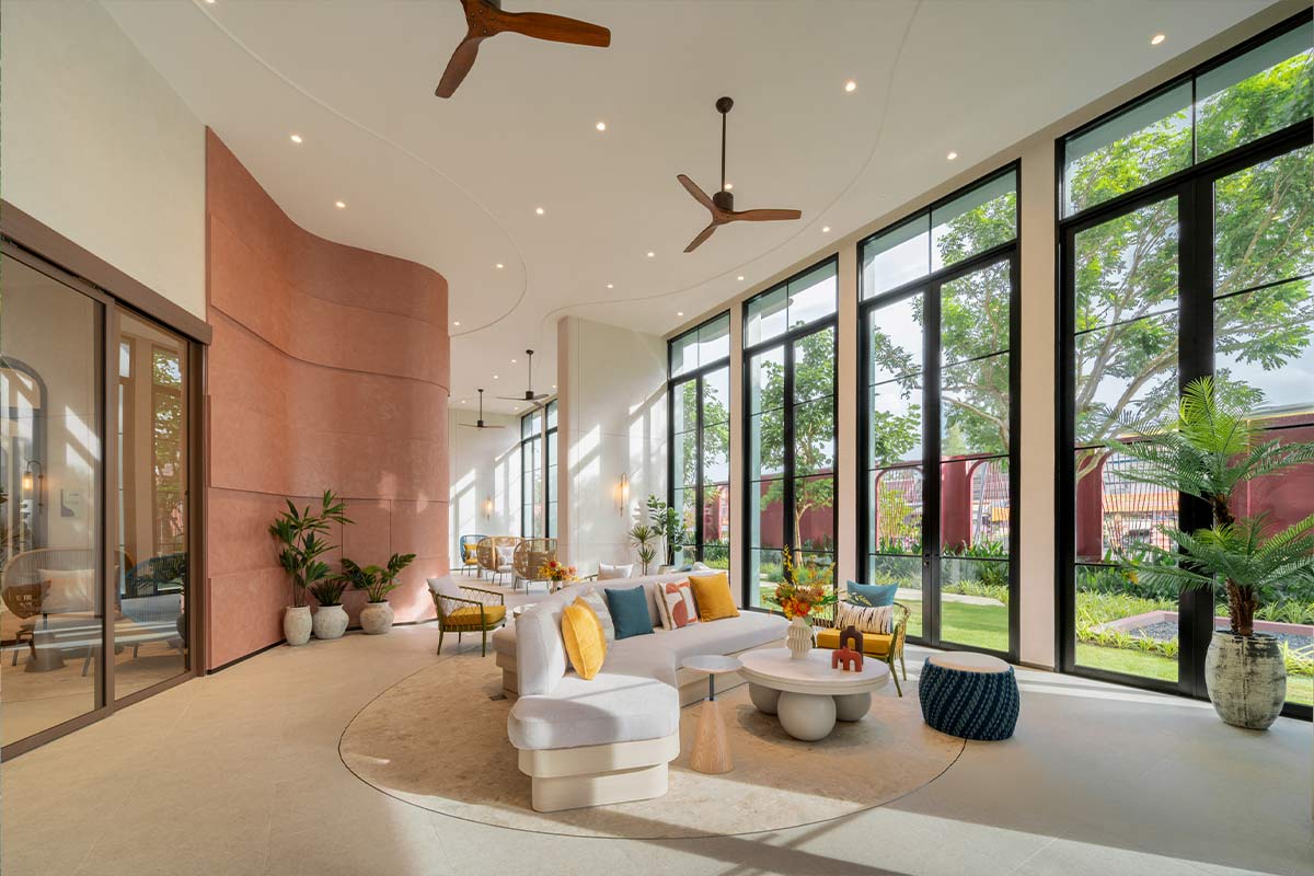 The double-height lobby: a curved terracotta wall, timber ceiling fans and full-height glazing onto the lawn