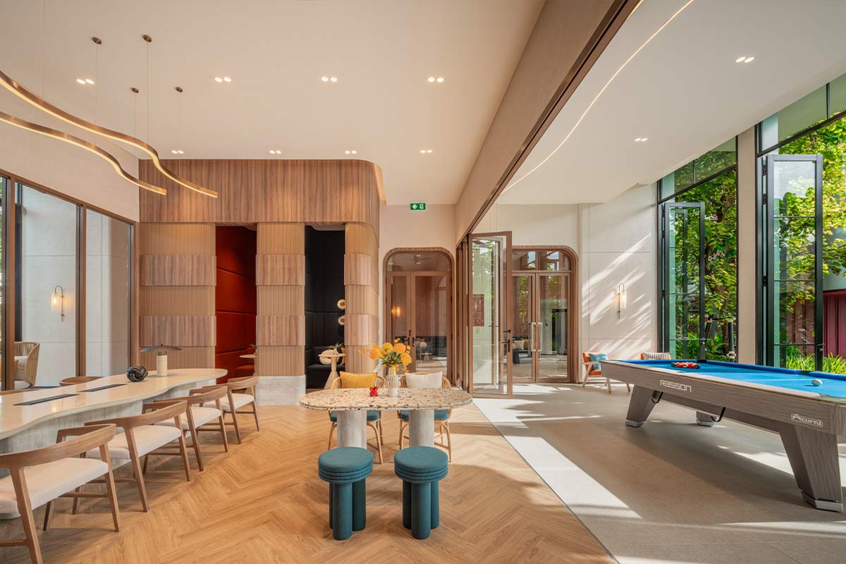 Co-working and entertainment in one volume: a long table with chairs, a round terrazzo table and a billiard table by the panoramic windows on the right