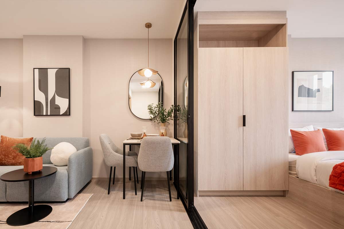 The show unit: a grey sofa and a dining table by the mirror, a glass partition, a light wardrobe and the bed behind it