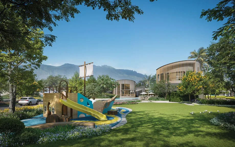 A playground with a ship-shaped slide beside a stream, the clubhouse with timber louvres across the lawn, mountains on the horizon