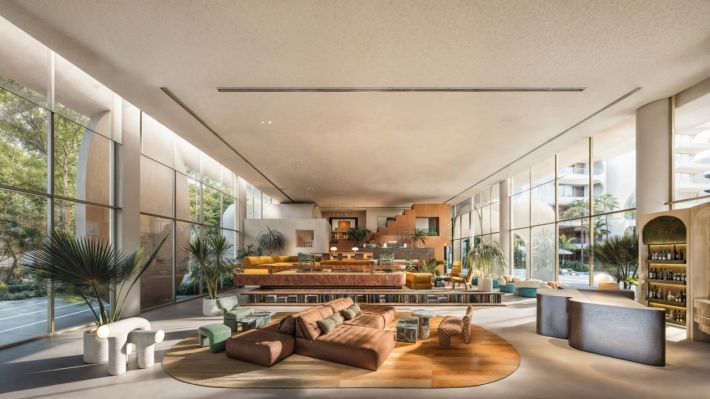 Lobby: a long glazed hall with an orange staircase at the far end and low modular sofas