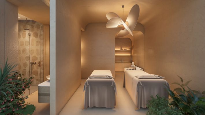 A spa room for two: a pair of massage tables under a shell-shaped light, a shower behind the partition